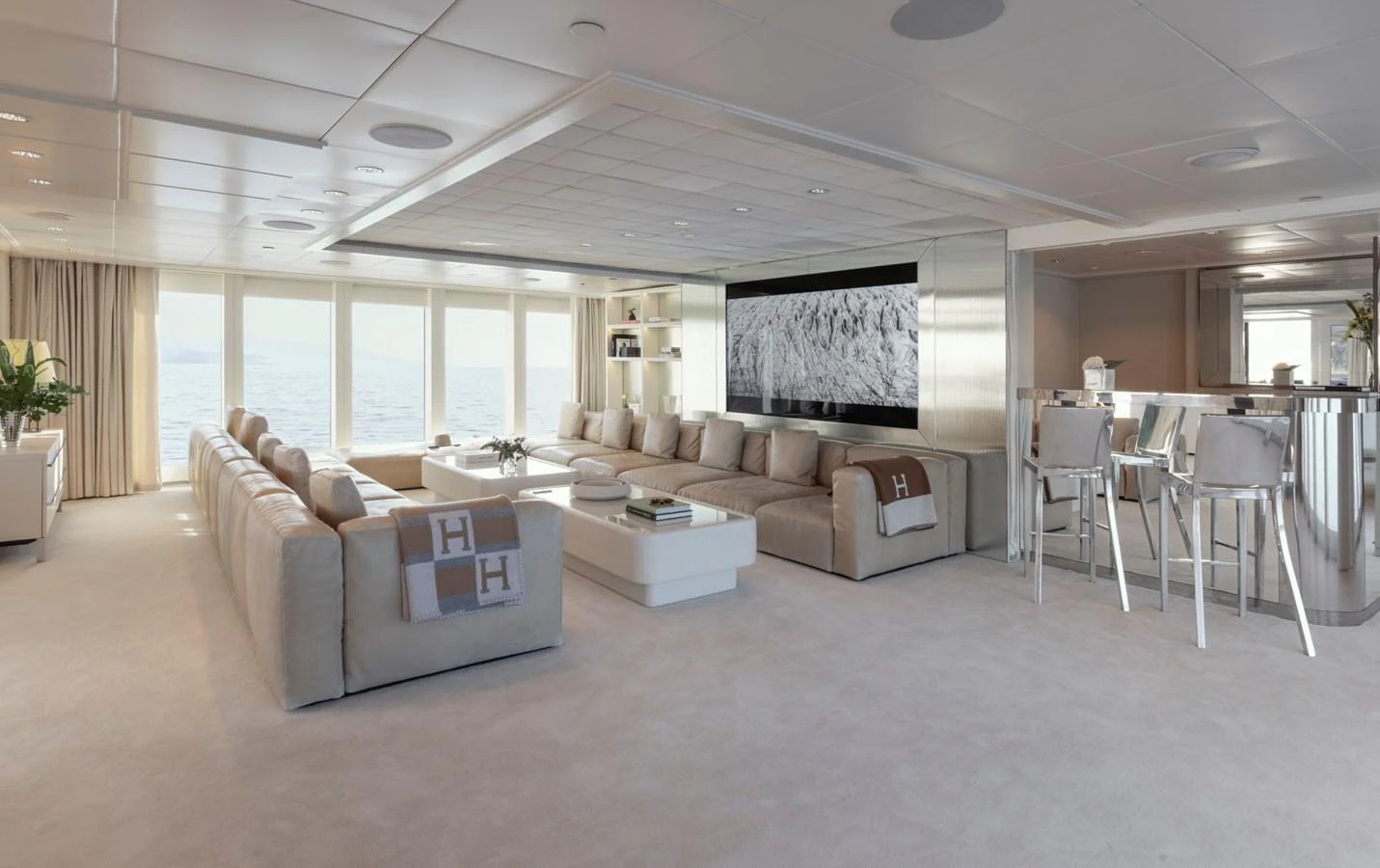 The spacious salon features plush seating, a large flat-screen TV, and a modern bar area, all with panoramic ocean views. aboard IDOL Yacht for Sale