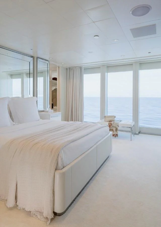 A serene stateroom with a large bed and expansive ocean views through floor-to-ceiling windows. aboard IDOL Yacht for Sale