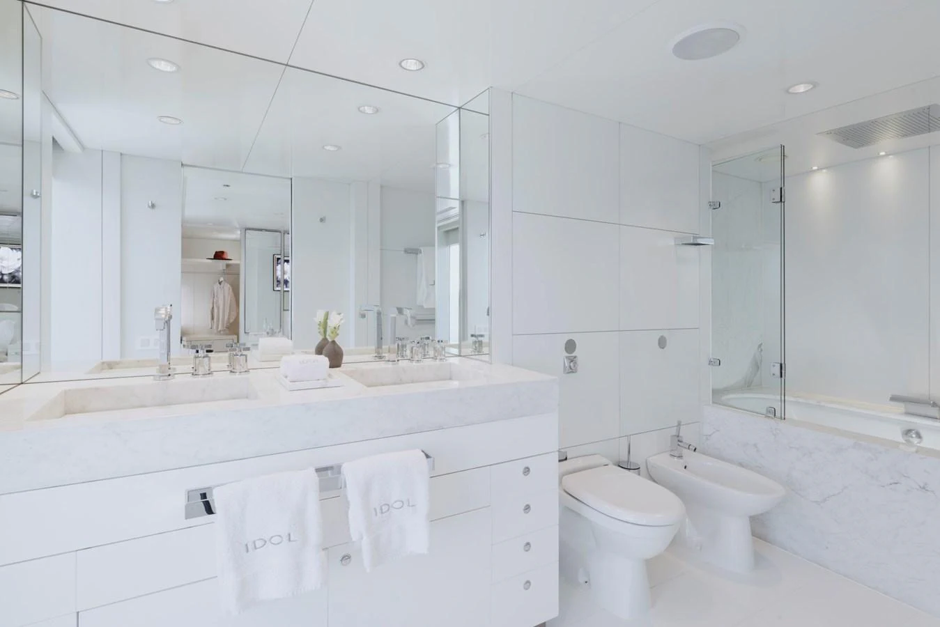 A pristine, modern bathroom with dual sinks and a glass-enclosed shower. aboard IDOL Yacht for Sale