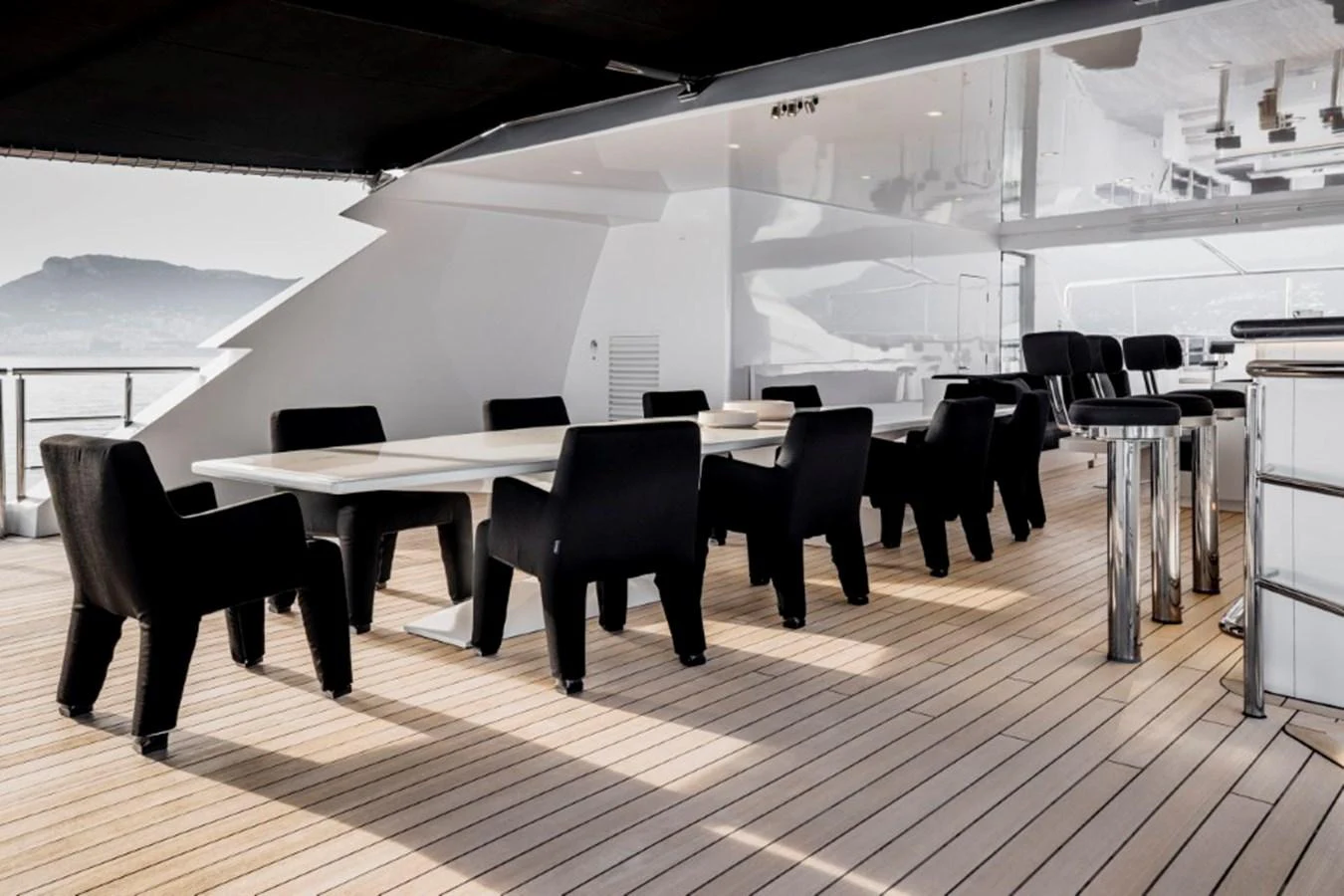 The aft deck features a spacious dining area with sleek black chairs and modern tables, perfect for alfresco dining. aboard IDOL Yacht for Sale