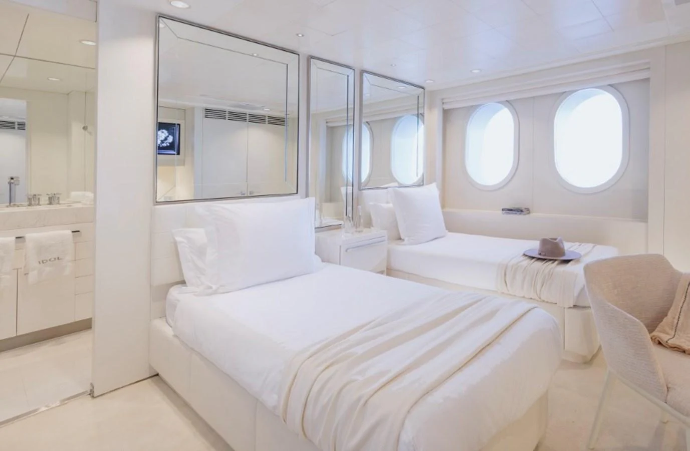 A serene guest stateroom featuring twin beds and large porthole windows. aboard IDOL Yacht for Sale