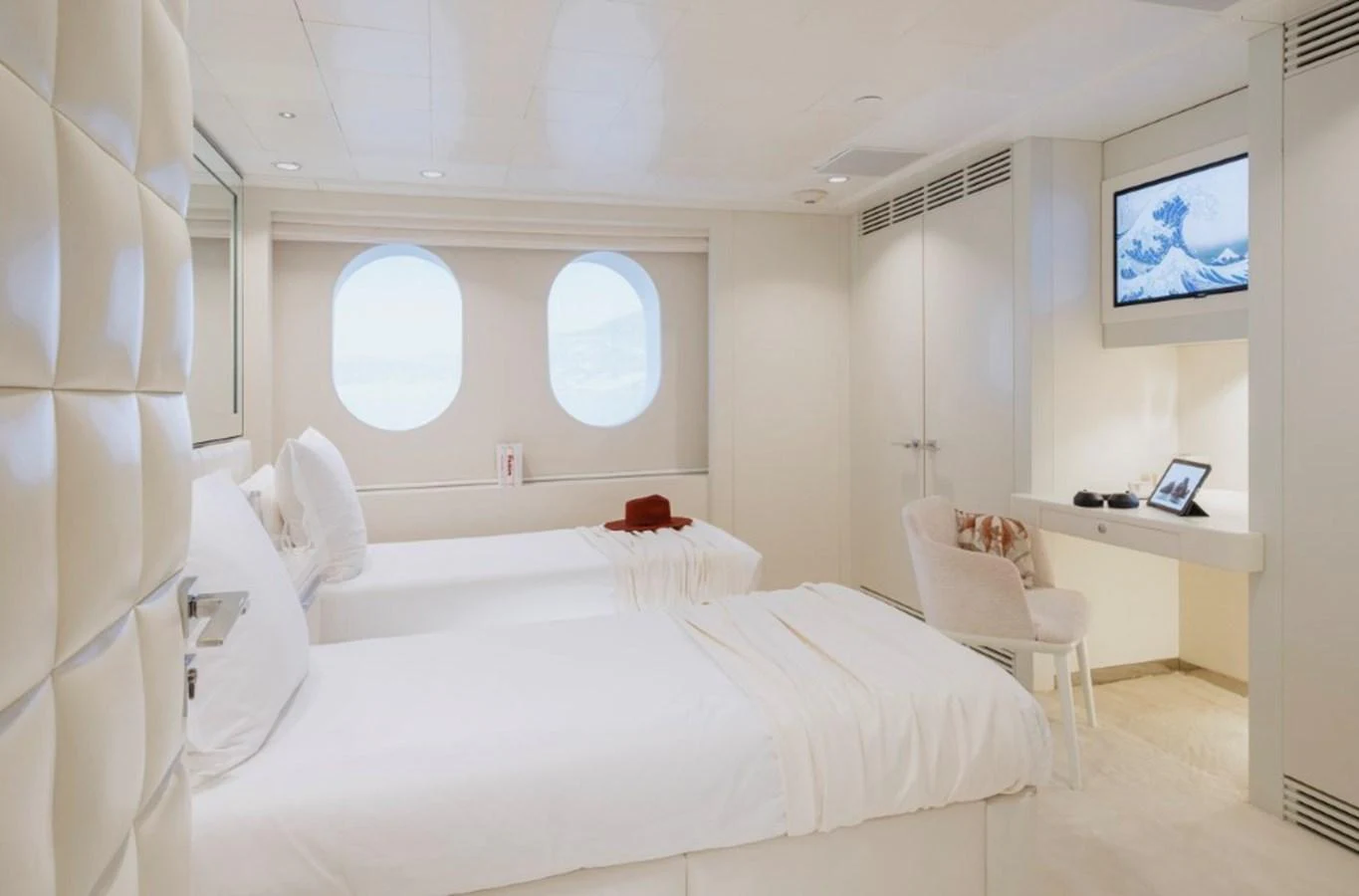 The stateroom features twin beds, a desk area, and large porthole windows for natural light. aboard IDOL Yacht for Sale