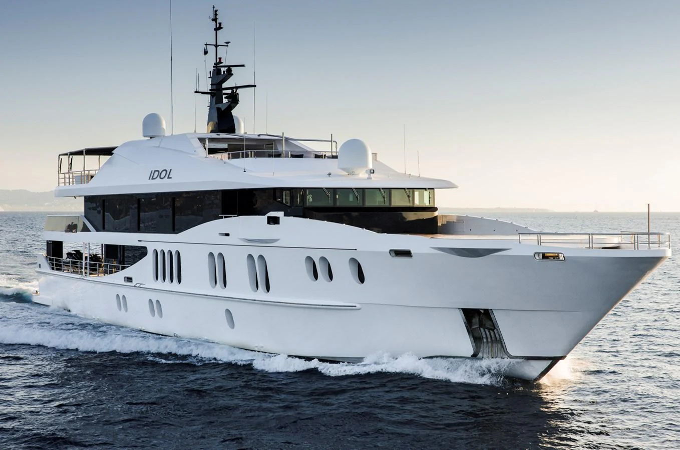A sleek and modern yacht cruising on calm waters at sunset. aboard IDOL Yacht for Sale