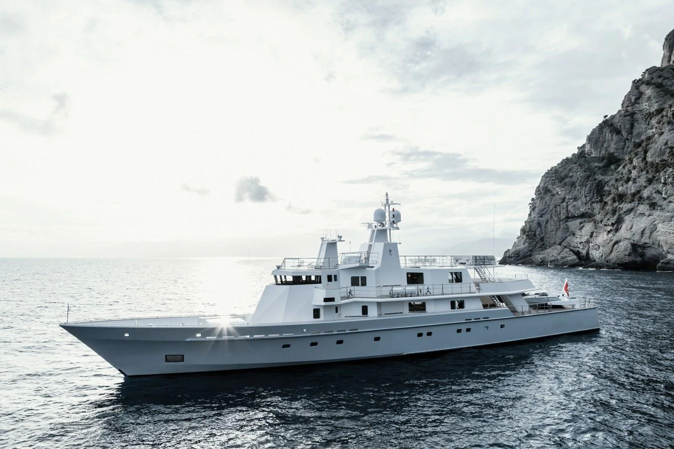 A sleek and modern yacht cruises gracefully along a rocky coastline. aboard RONIN Yacht for Sale
