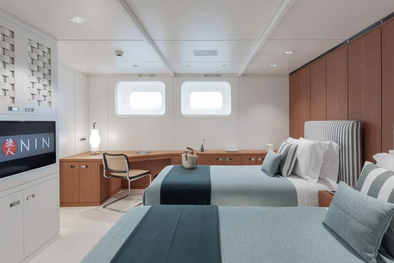 The guest stateroom features twin beds, a desk area, and modern decor with ample natural light. aboard RONIN Yacht for Sale