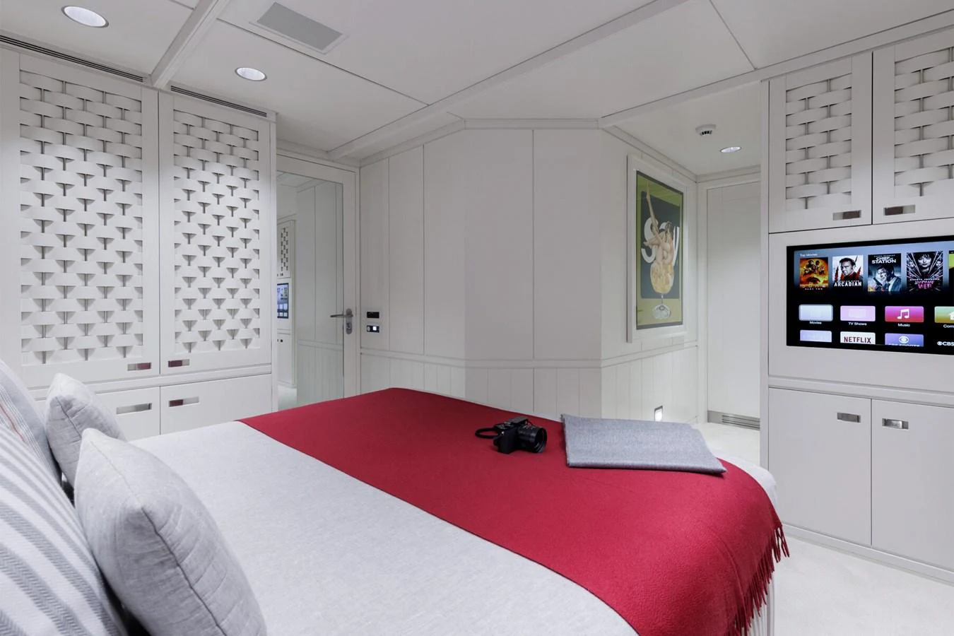 The stateroom features a comfortable bed with a red blanket and a modern entertainment system. aboard RONIN Yacht for Sale