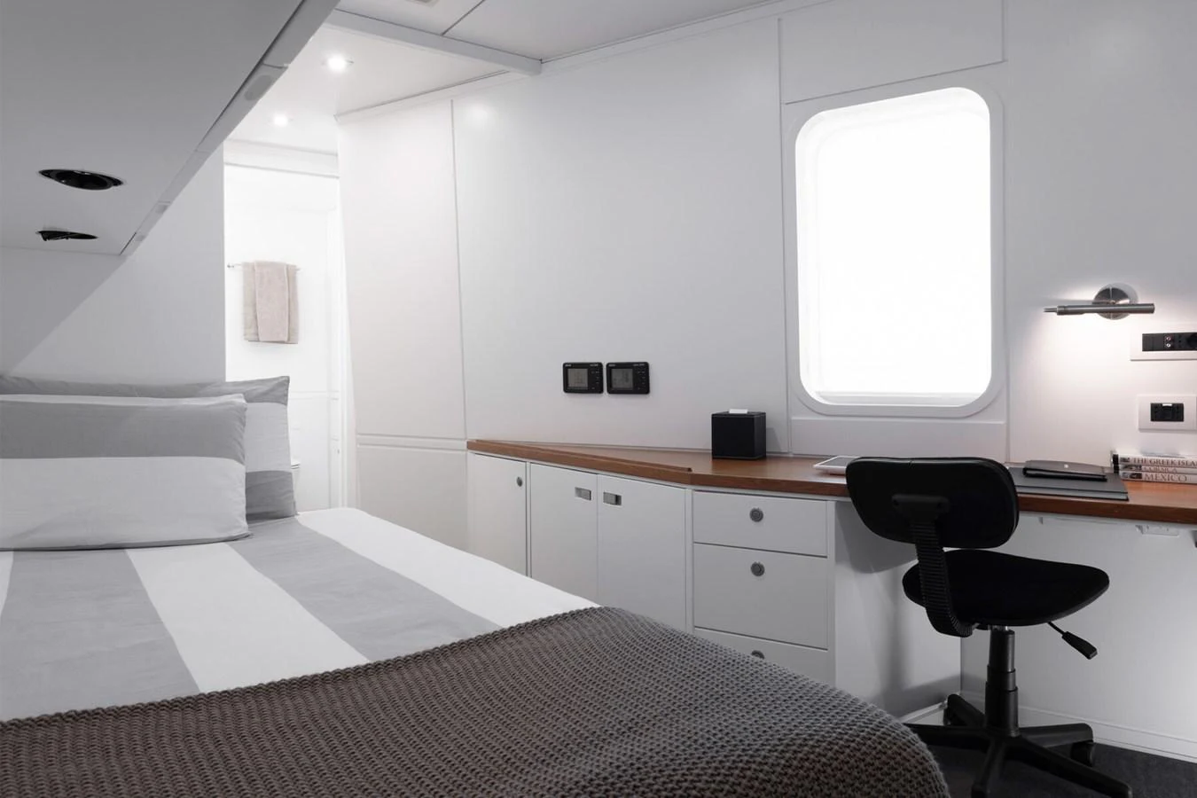 A cozy stateroom with a comfortable bed and a functional desk area. aboard RONIN Yacht for Sale
