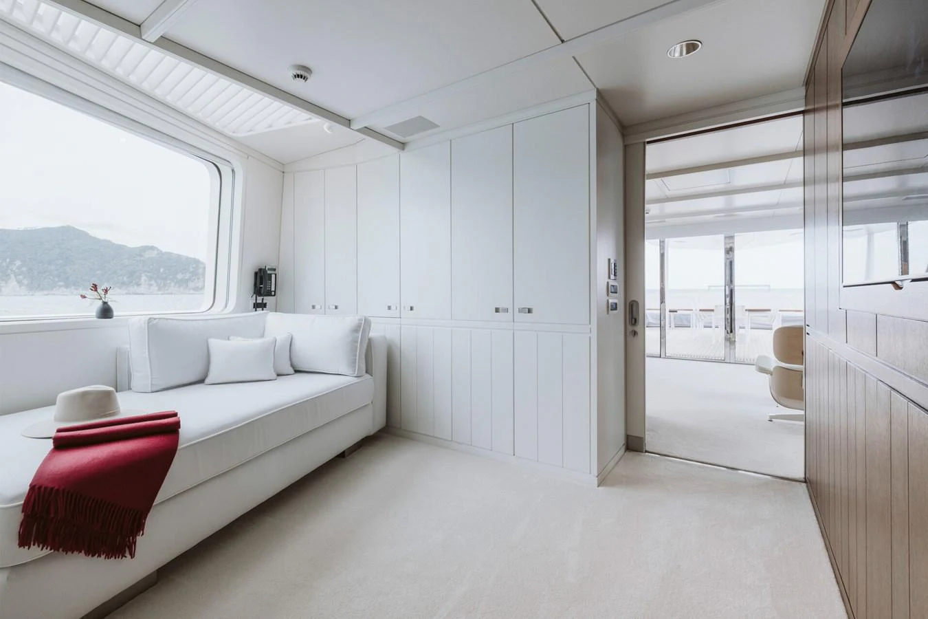 A serene cabin with a large window, white furnishings, and a cozy seating area. aboard RONIN Yacht for Sale