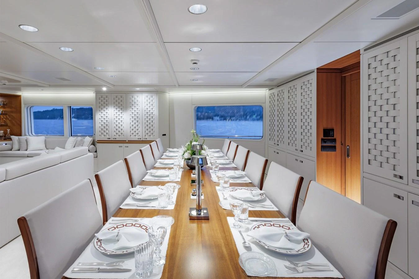 The yacht's dining area features a long table elegantly set for a formal meal, surrounded by plush seating and modern decor. aboard RONIN Yacht for Sale