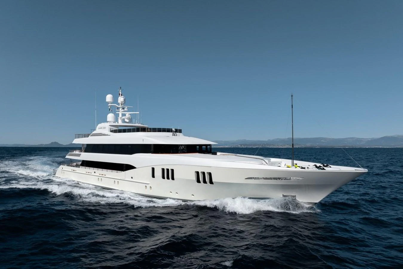 A sleek, modern yacht glides effortlessly through the open sea under a clear blue sky. aboard CARPE DIEM Yacht for Sale
