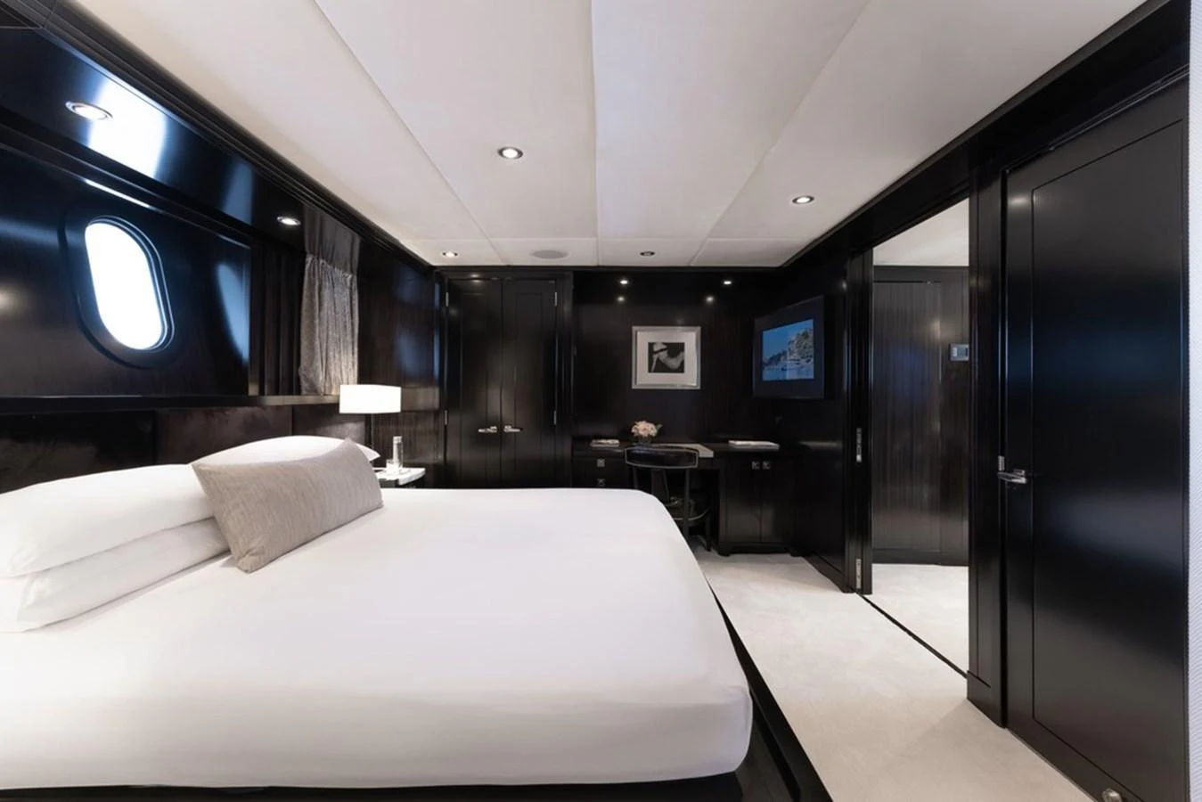 The stateroom features a luxurious bed with elegant dark wood finishes and modern lighting. aboard CARPE DIEM Yacht for Sale