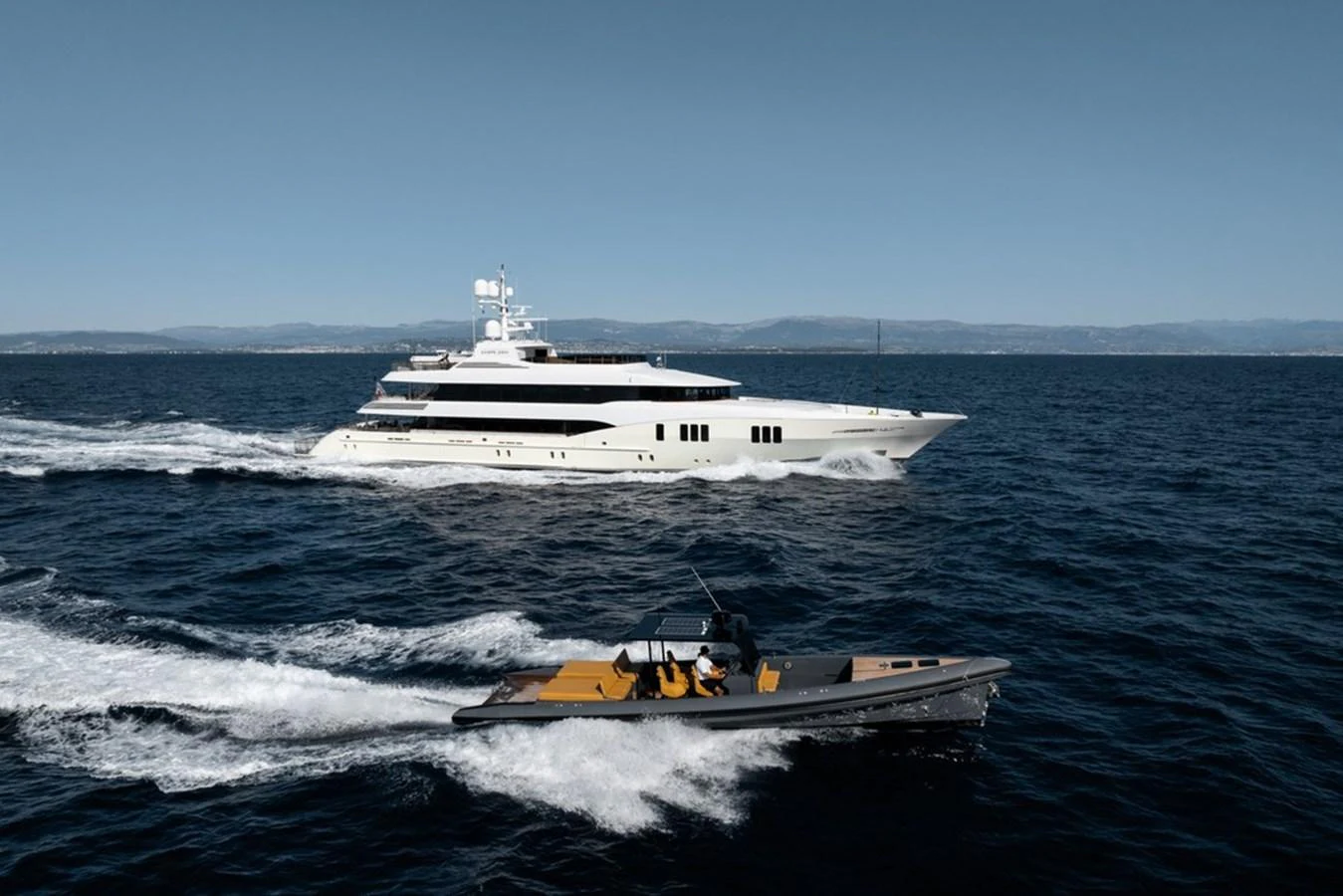 A sleek yacht cruises through the open sea, accompanied by a smaller tender boat. aboard CARPE DIEM Yacht for Sale
