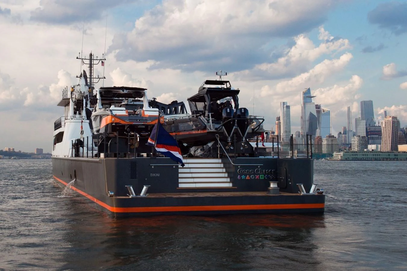 The yacht is seen from the rear, showcasing its robust design and cityscape backdrop. aboard GENE CHASER Yacht for Sale