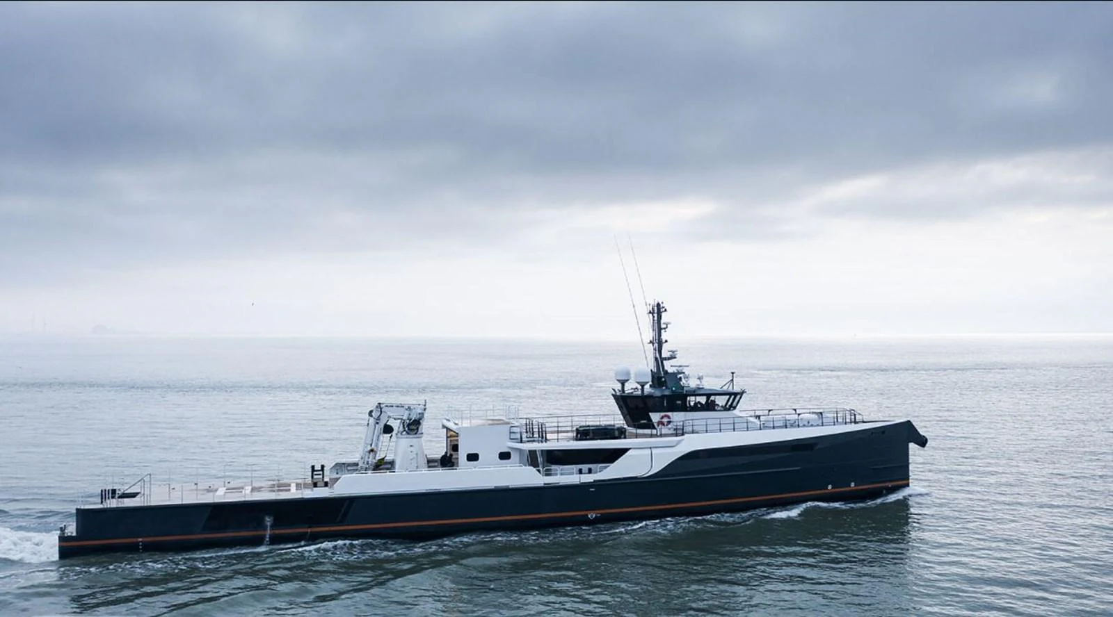 A sleek, modern yacht cruises through calm waters under a cloudy sky. aboard GENE CHASER Yacht for Sale