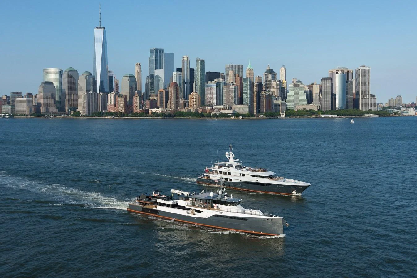 Two yachts cruise along a city skyline, showcasing their sleek designs and luxurious presence on the water. aboard GENE CHASER Yacht for Sale