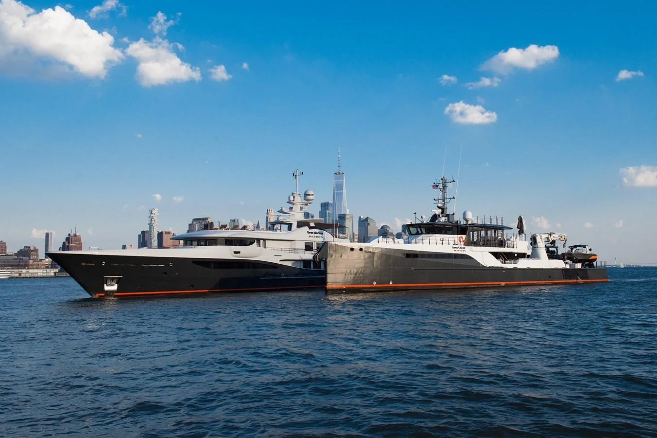 A sleek yacht glides through the water with a city skyline in the background. aboard GENE CHASER Yacht for Sale