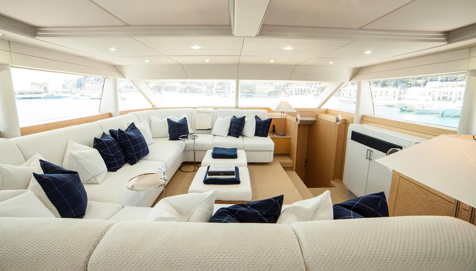 The salon features a spacious and elegant seating area with plush white upholstery and navy blue accents. aboard OCEANA I Yacht for Sale