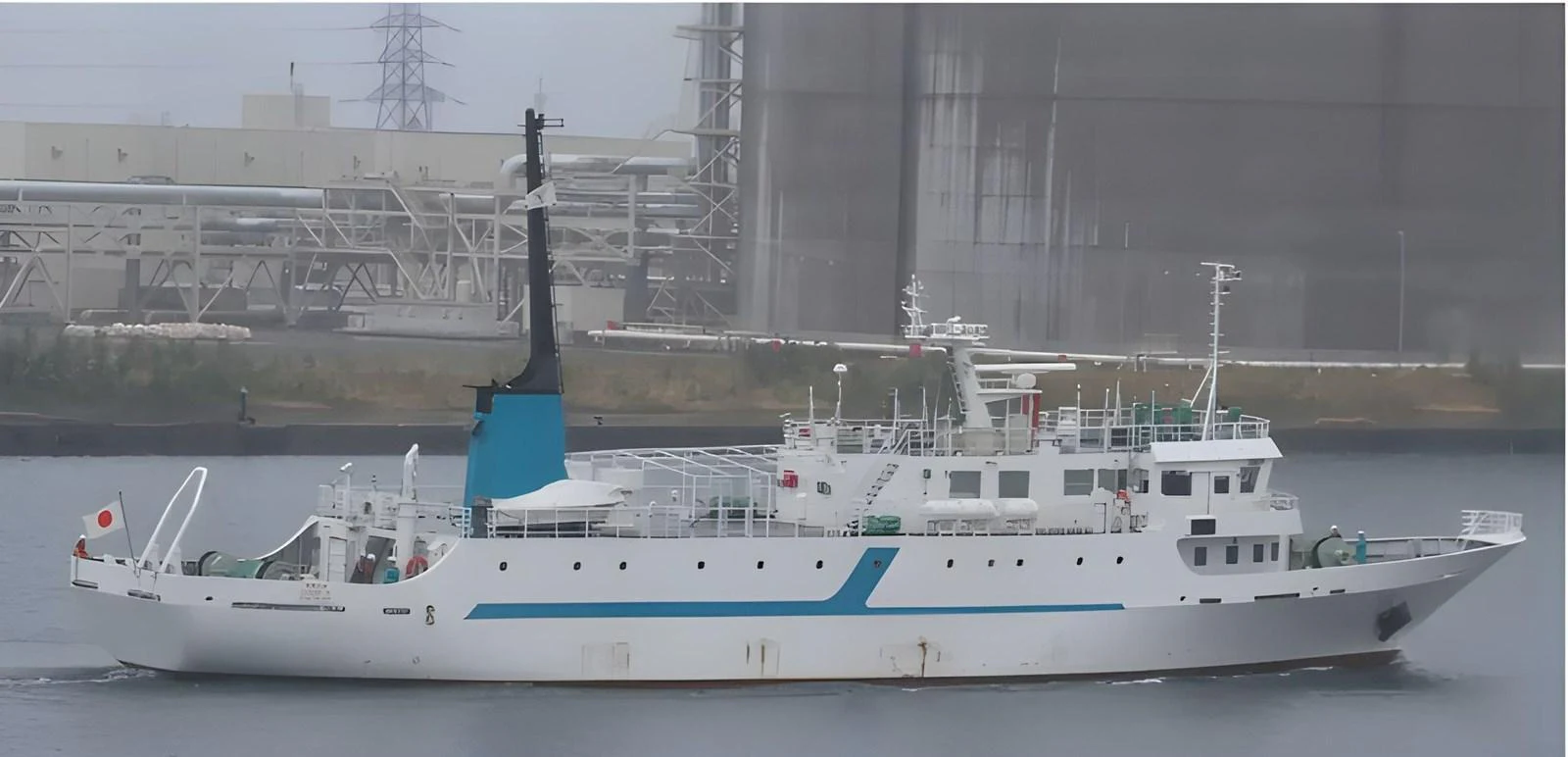 A sleek yacht is seen docked in an industrial harbor, showcasing its modern design and clean lines. aboard CUSTOM Yacht for Sale