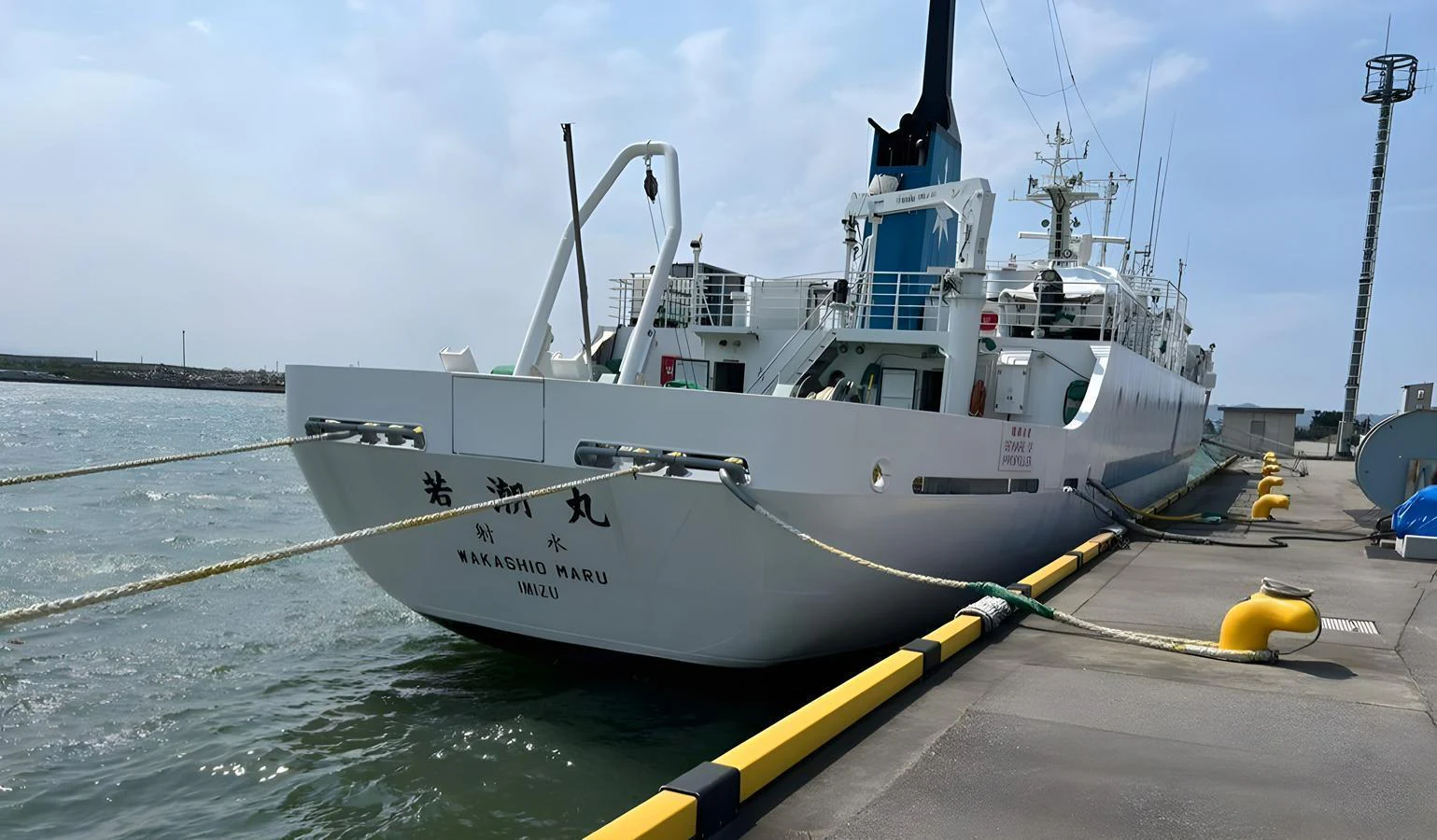 A yacht is docked at a pier, showcasing its stern and side profile. aboard CUSTOM Yacht for Sale