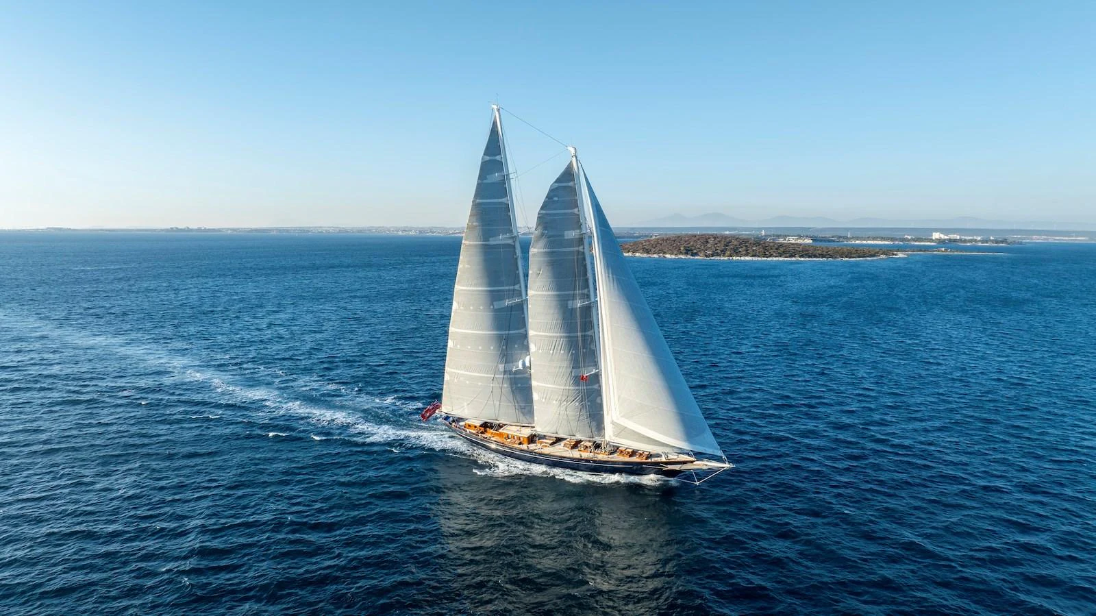 A stunning sailing yacht glides gracefully across the open sea under clear blue skies. aboard METEOR Yacht for Sale