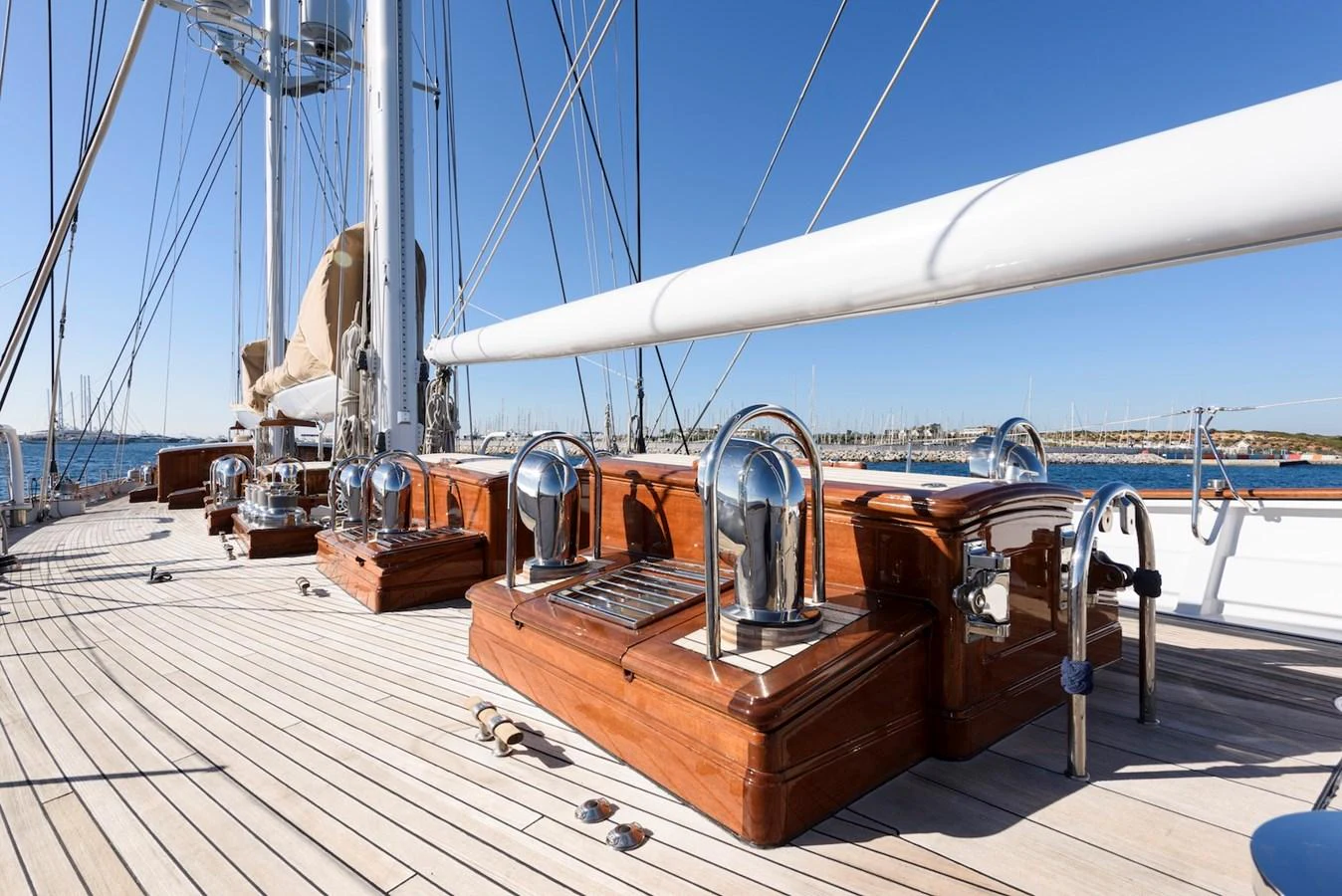 The deck features polished wood and chrome details under a clear blue sky. aboard METEOR Yacht for Sale