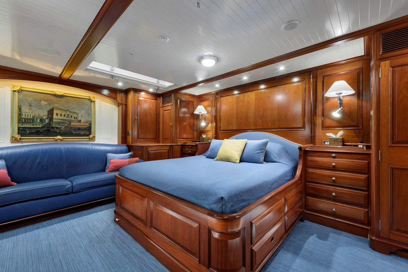 The stateroom features rich wood paneling, a comfortable bed, and a cozy seating area. aboard METEOR Yacht for Sale