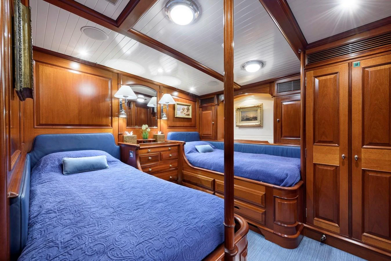 The guest stateroom features rich wood paneling and twin beds with blue bedding, creating a cozy and elegant atmosphere. aboard METEOR Yacht for Sale