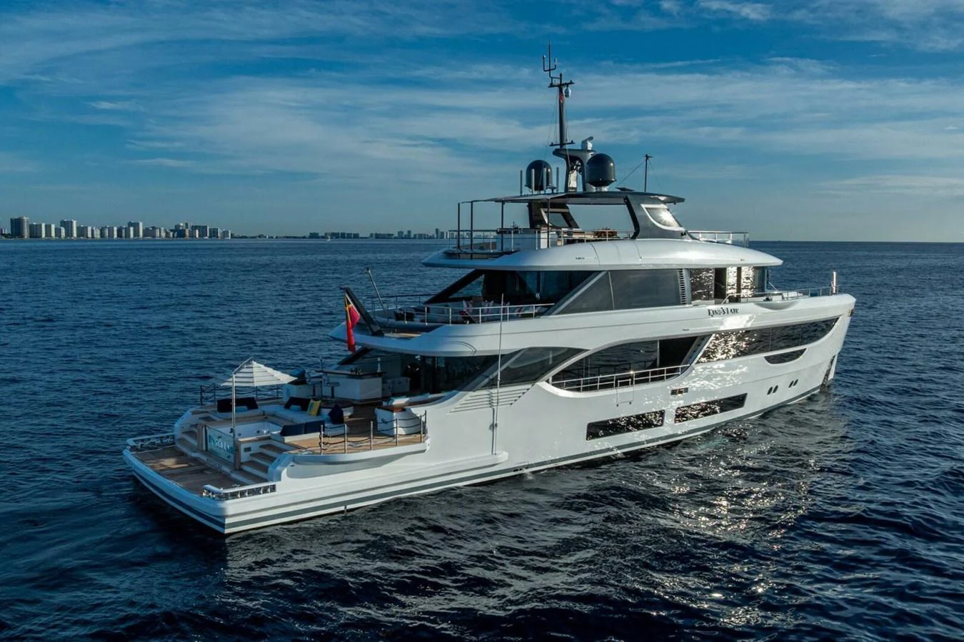 A sleek and modern yacht glides gracefully on the open water under a clear blue sky. aboard KING'S LAIR Yacht for Sale