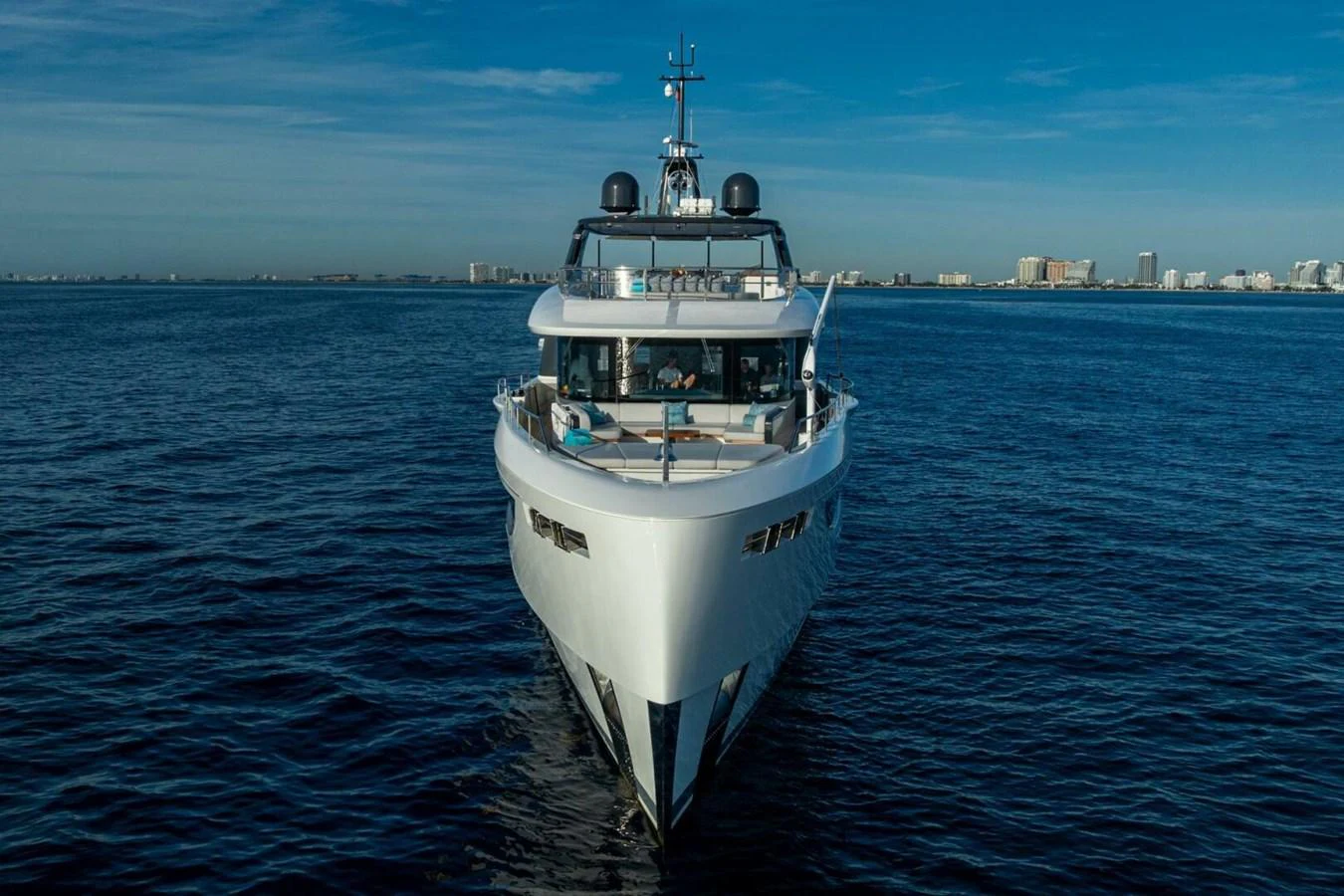 A sleek yacht cruises on calm waters with a cityscape in the background. aboard KING'S LAIR Yacht for Sale