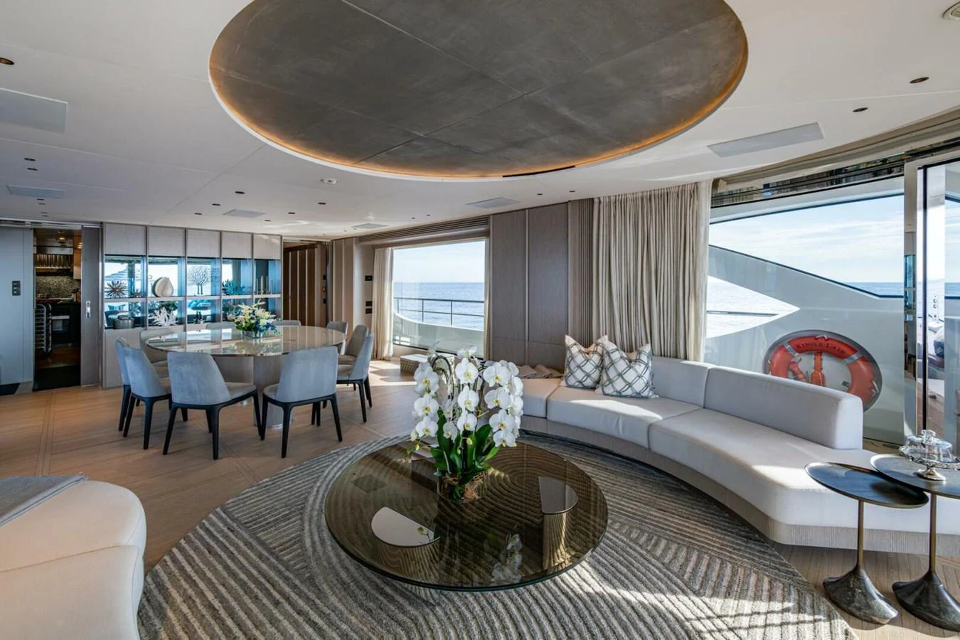 The salon features elegant seating, a dining area, and large windows offering stunning ocean views. aboard KING'S LAIR Yacht for Sale