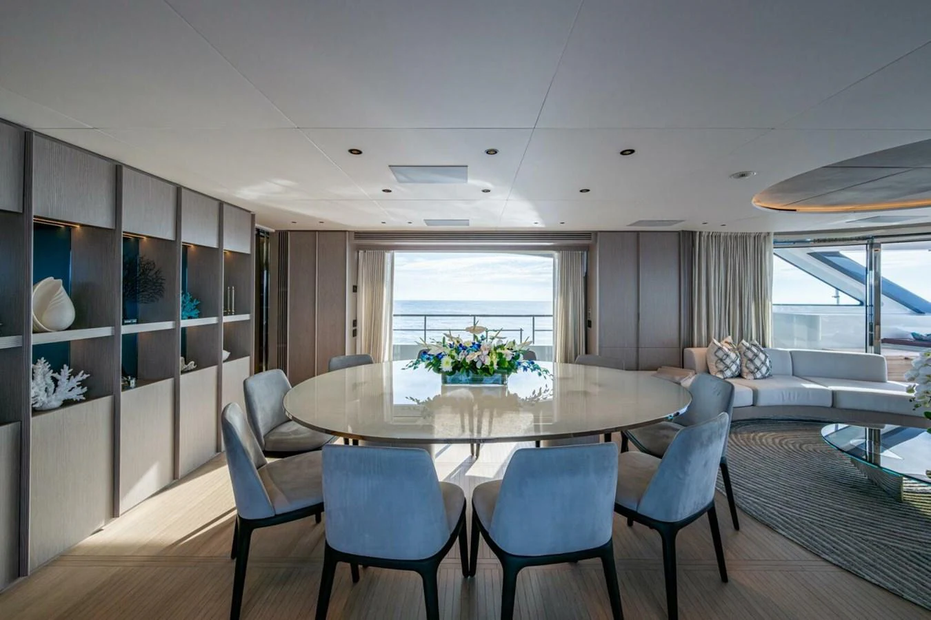 The yacht's dining area features a round table with plush chairs, offering a luxurious setting with a view of the sea. aboard KING'S LAIR Yacht for Sale
