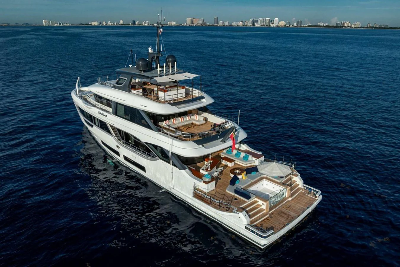 A luxurious yacht cruising on calm waters with a spacious aft deck featuring a pool and lounging areas. aboard KING'S LAIR Yacht for Sale