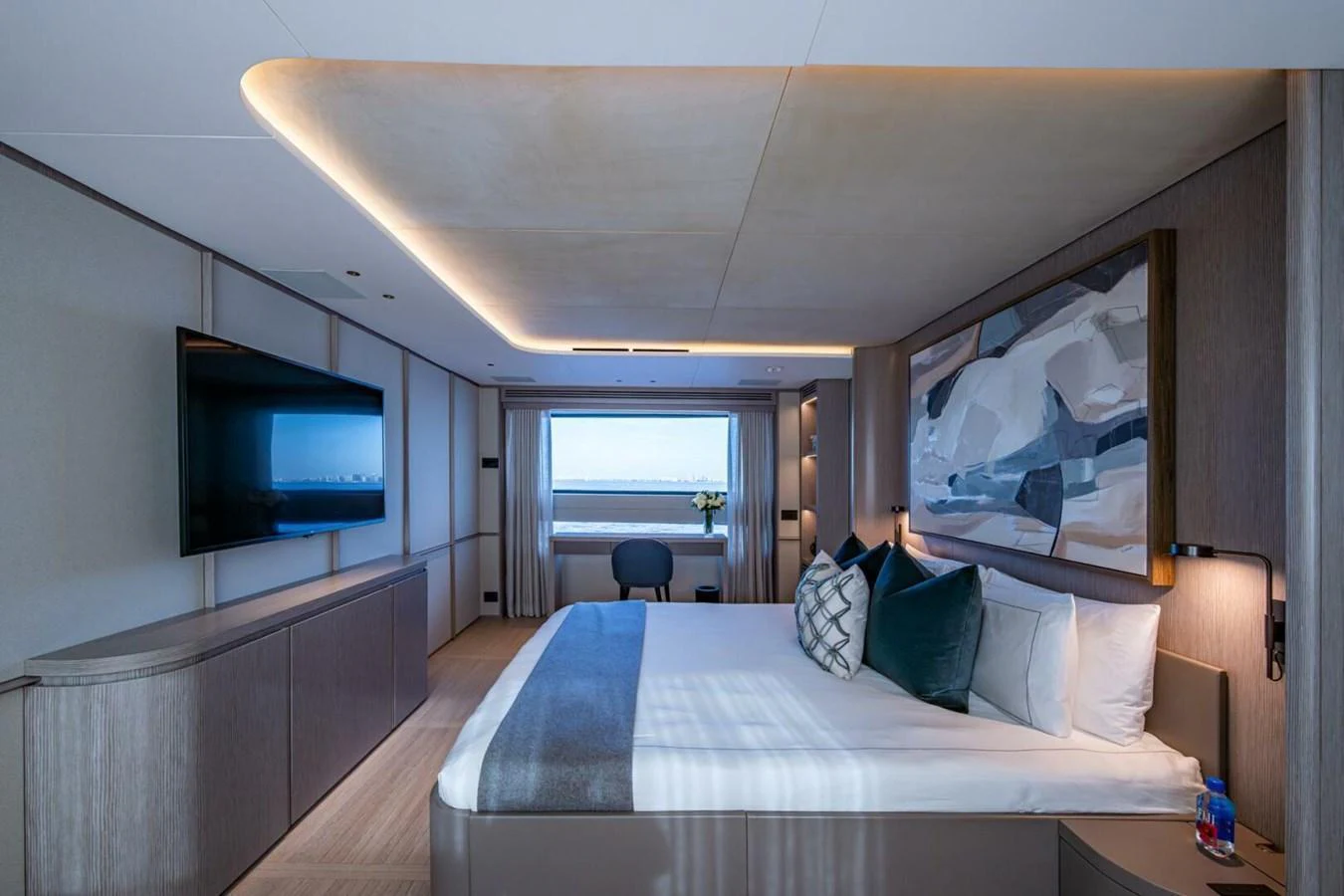 The master stateroom features a luxurious bed, modern decor, and a large window with an ocean view. aboard KING'S LAIR Yacht for Sale