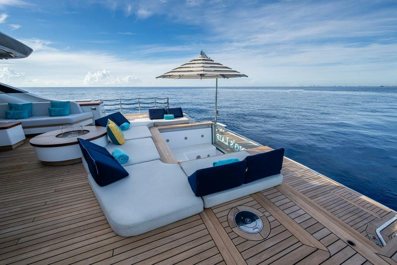 The aft deck features a luxurious jacuzzi surrounded by plush seating and an umbrella, offering a perfect spot for relaxation with stunning ocean views. aboard KING'S LAIR Yacht for Sale