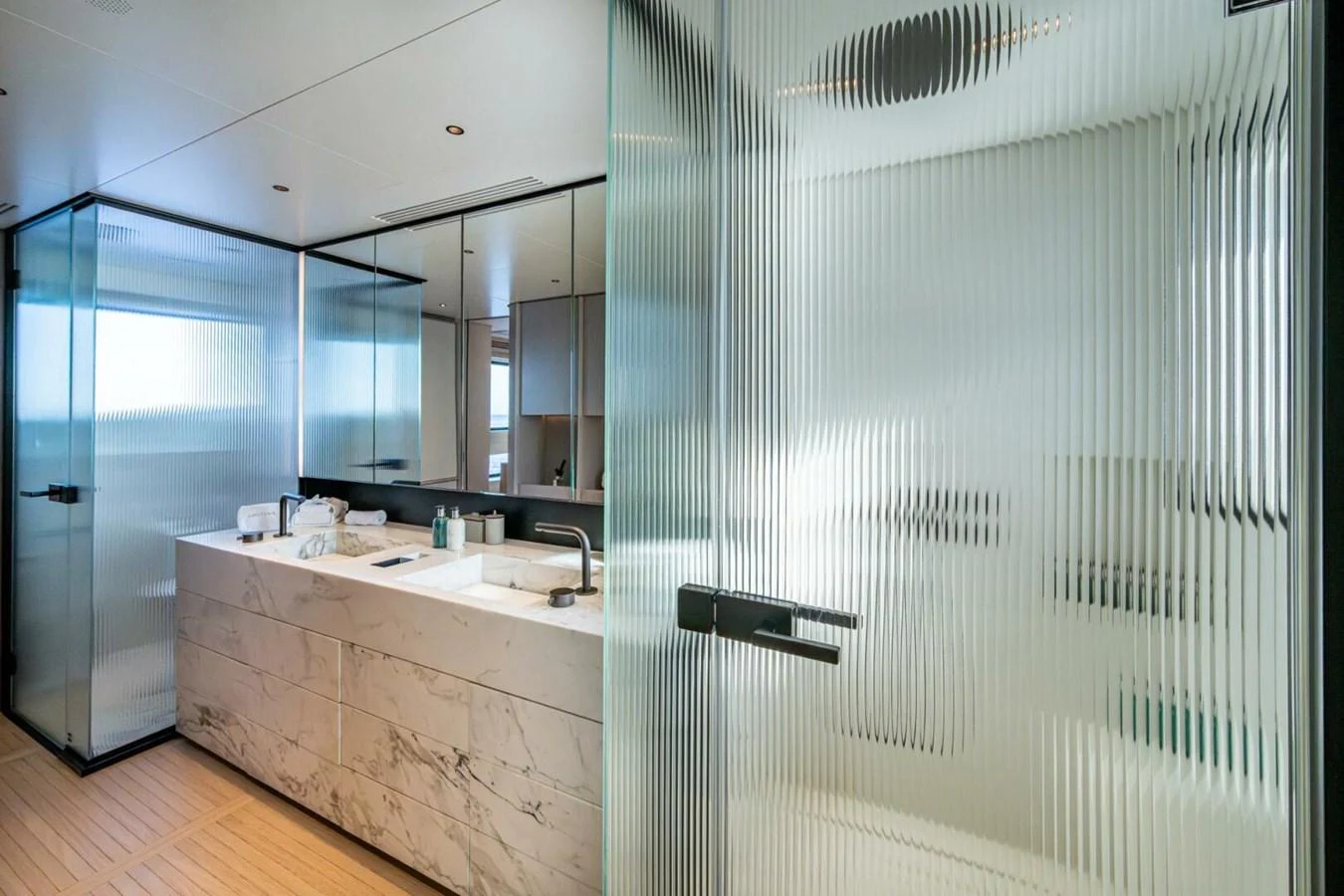 The yacht's bathroom features a modern design with frosted glass partitions and a sleek marble countertop. aboard KING'S LAIR Yacht for Sale