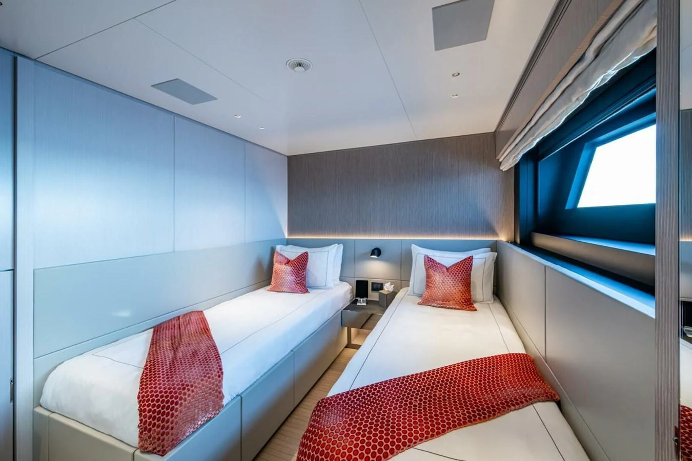 The twin stateroom features modern decor with two single beds and stylish red accents. aboard KING'S LAIR Yacht for Sale