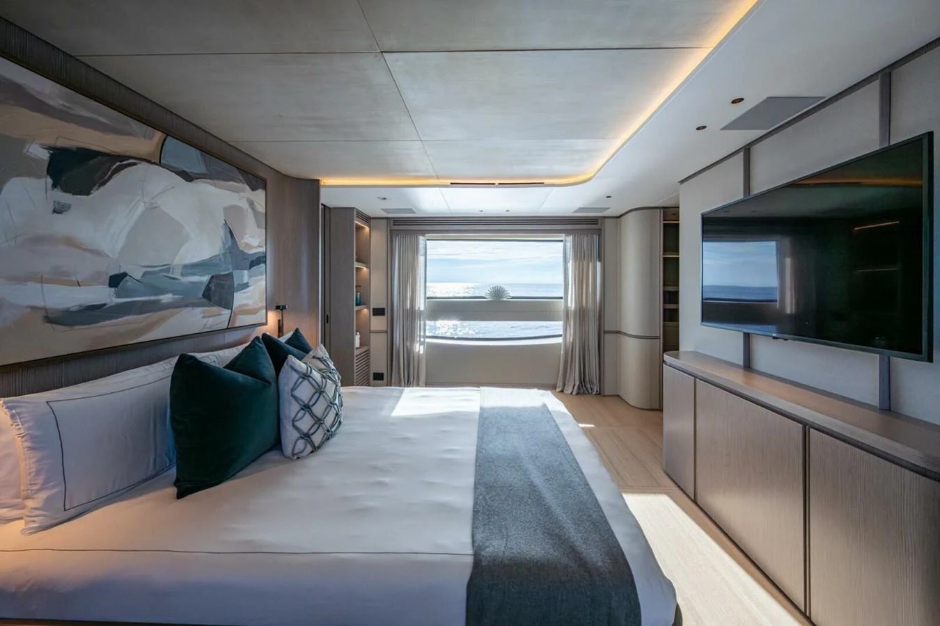 The master stateroom features a large bed, modern decor, and a flat-screen TV, with a window offering a stunning sea view. aboard KING'S LAIR Yacht for Sale