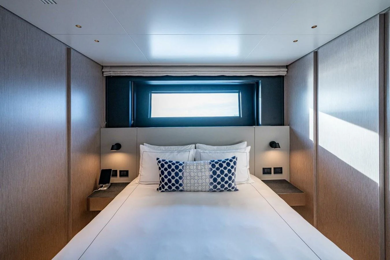 The stateroom features a luxurious bed with elegant bedding and modern lighting. aboard KING'S LAIR Yacht for Sale