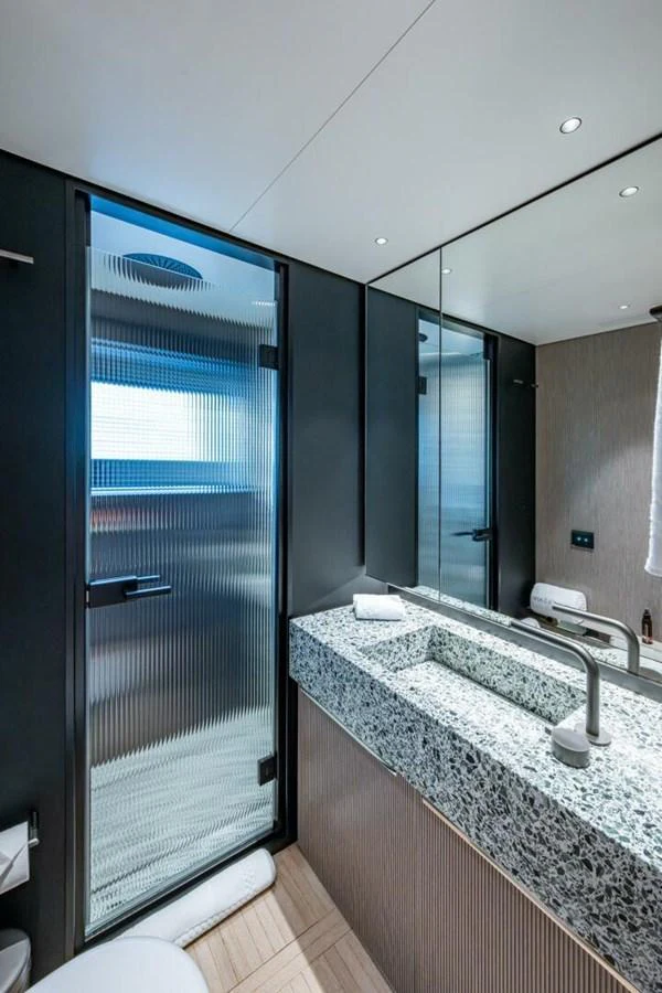 The yacht's bathroom features a sleek design with a modern sink and a frosted glass shower enclosure. aboard KING'S LAIR Yacht for Sale