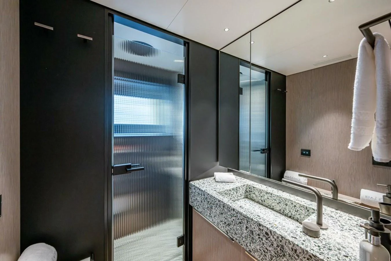 A modern yacht bathroom featuring a sleek design with a granite countertop and frosted glass shower door. aboard KING'S LAIR Yacht for Sale
