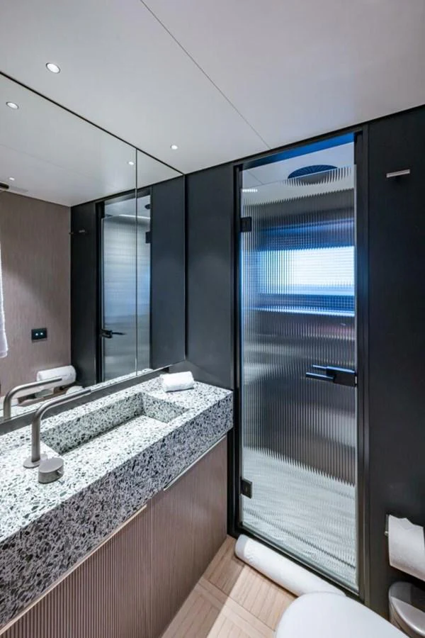The yacht's bathroom features a sleek design with a modern sink and a frosted glass shower door. aboard KING'S LAIR Yacht for Sale
