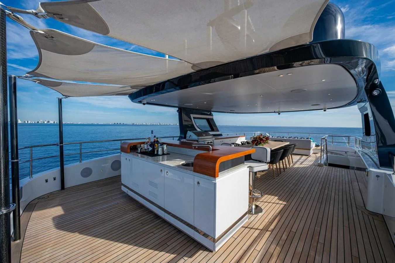 The sundeck features a spacious bar and dining area under elegant shade sails, perfect for entertaining while enjoying panoramic ocean views. aboard KING'S LAIR Yacht for Sale