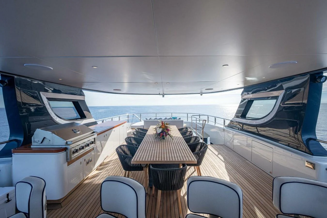 The aft deck features a spacious dining area with a large table and comfortable seating, perfect for alfresco meals with a view of the sea. aboard KING'S LAIR Yacht for Sale