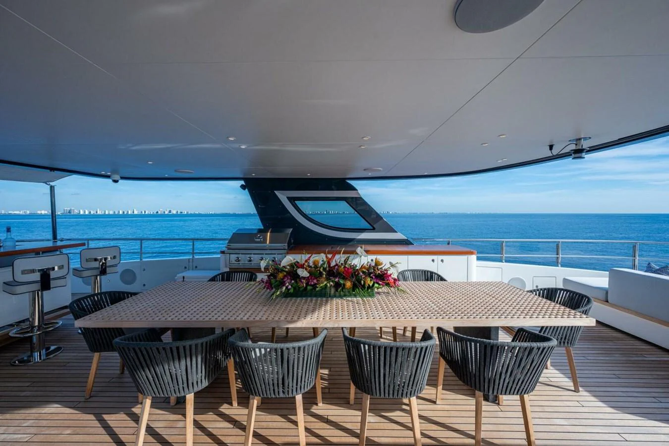 The aft deck features a spacious dining area with a large table and comfortable seating, perfect for alfresco dining with a stunning ocean view. aboard KING'S LAIR Yacht for Sale