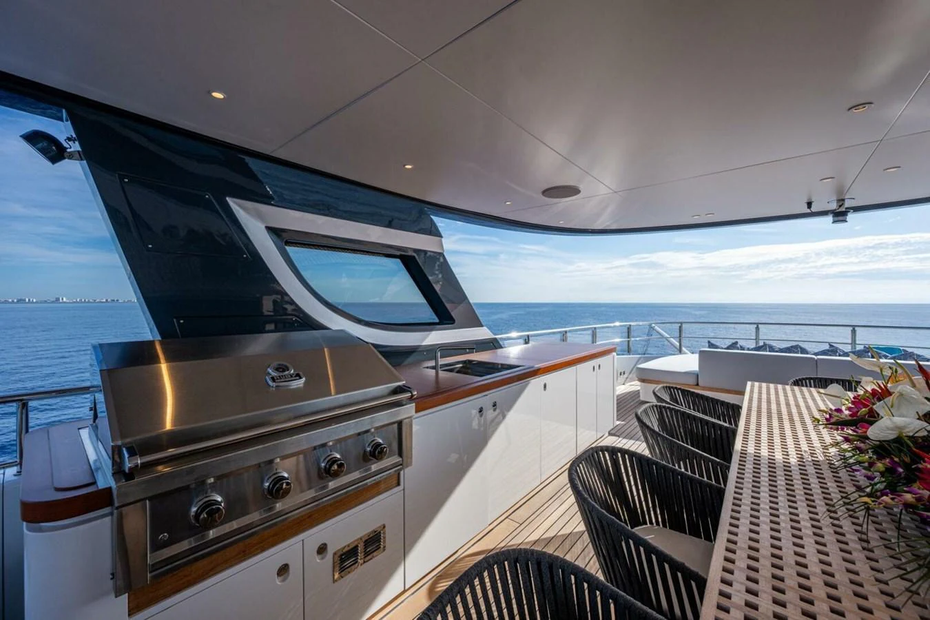 The aft deck features a stylish outdoor dining area with a built-in grill, perfect for alfresco meals with a view of the sea. aboard KING'S LAIR Yacht for Sale