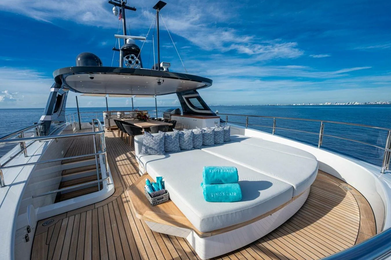 The sundeck offers a luxurious lounging area with plush sunbeds and a dining table, perfect for relaxation and entertainment. aboard KING'S LAIR Yacht for Sale