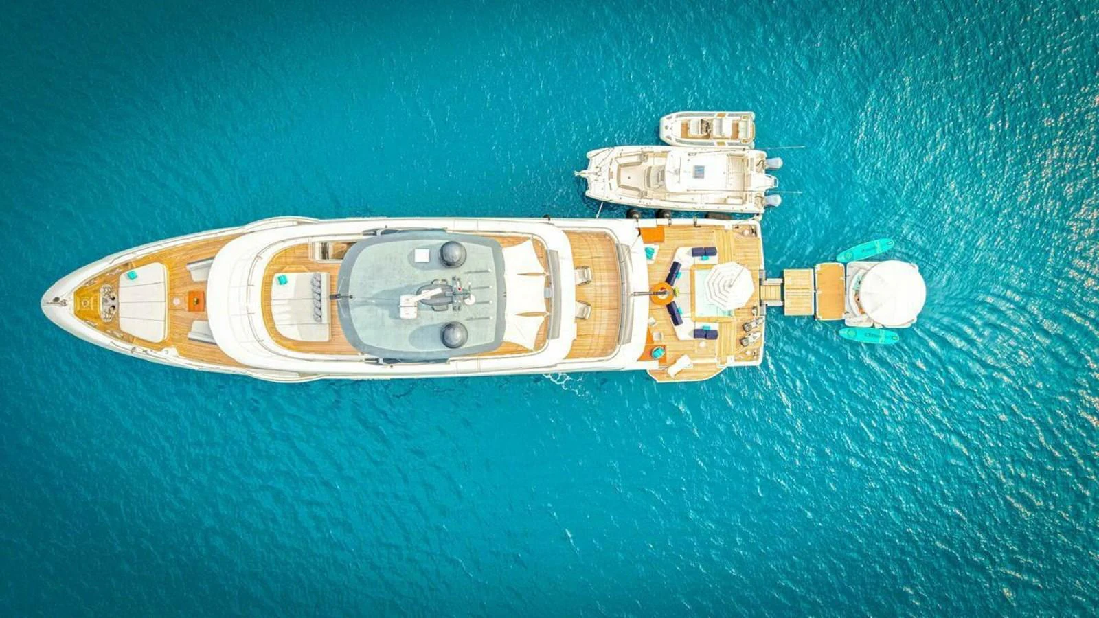 A stunning aerial view of a luxurious yacht docked alongside smaller vessels on clear blue waters. aboard KING'S LAIR Yacht for Sale