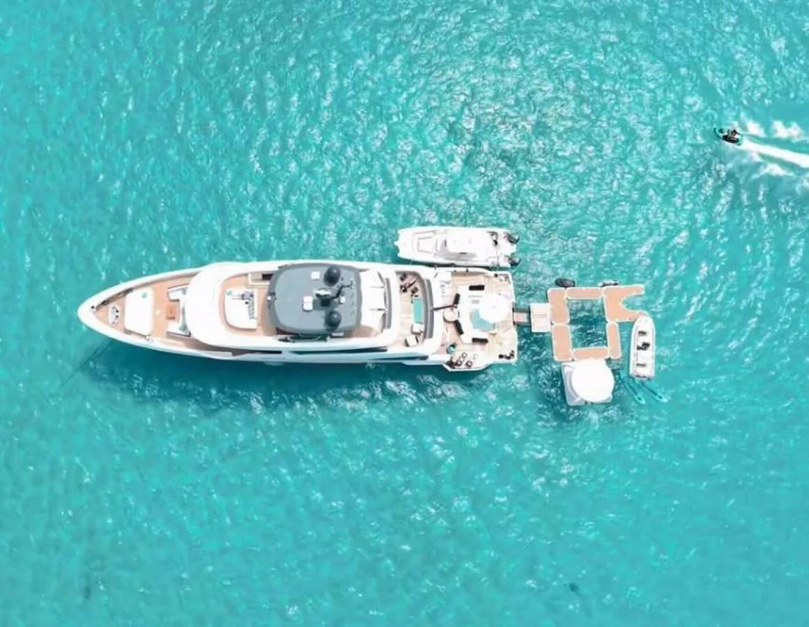 A stunning aerial view of a luxurious yacht anchored in crystal-clear waters, surrounded by various water toys and tenders. aboard KING'S LAIR Yacht for Sale