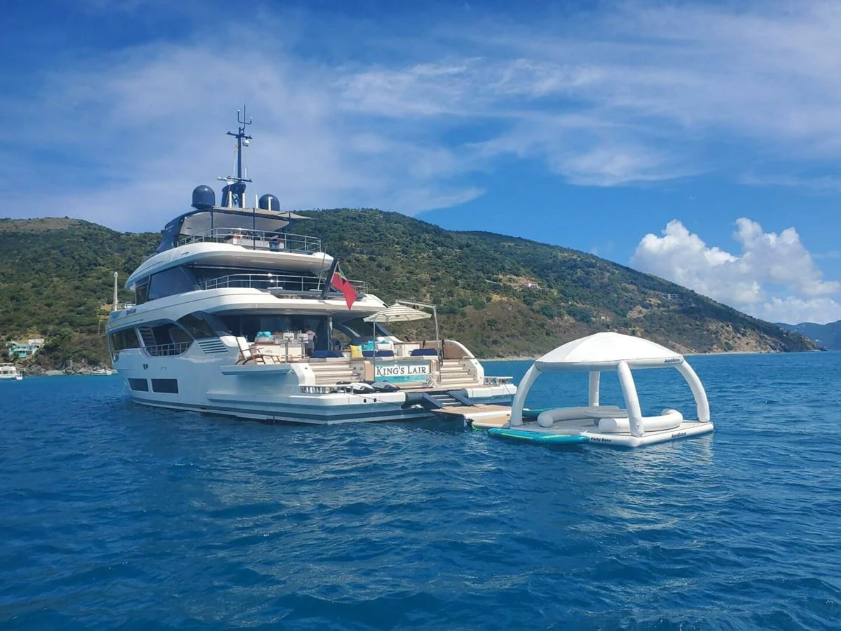 A luxurious yacht anchored in a serene bay with a floating lounge area nearby. aboard KING'S LAIR Yacht for Sale