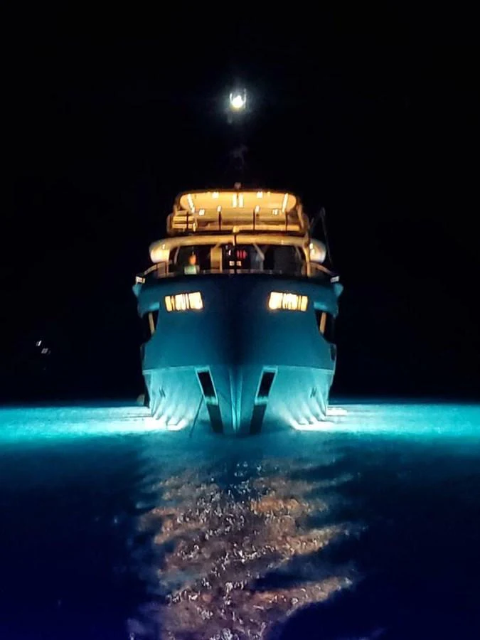 A yacht illuminated at night, creating a striking reflection on the water. aboard KING'S LAIR Yacht for Sale